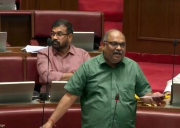 Man passing along documents in front of audience discussing religion freedom bill.